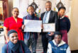 A group image of KwaNotshelwa High School learners and educators holding their certificate and cash-prize cheque.