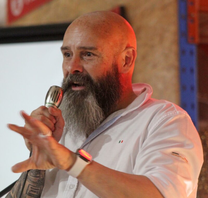 A bald male is photographed giving a speech during the 25 year celebration gala evening.