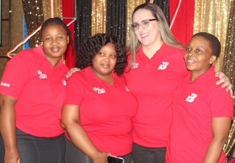 Several Build it Plus Newcastle employees are photographed in front of black, gold and red draping.