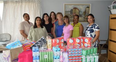 Several women are pictured posing behind a variety of sanitary items donated to the Newcastle Crisis Centre.