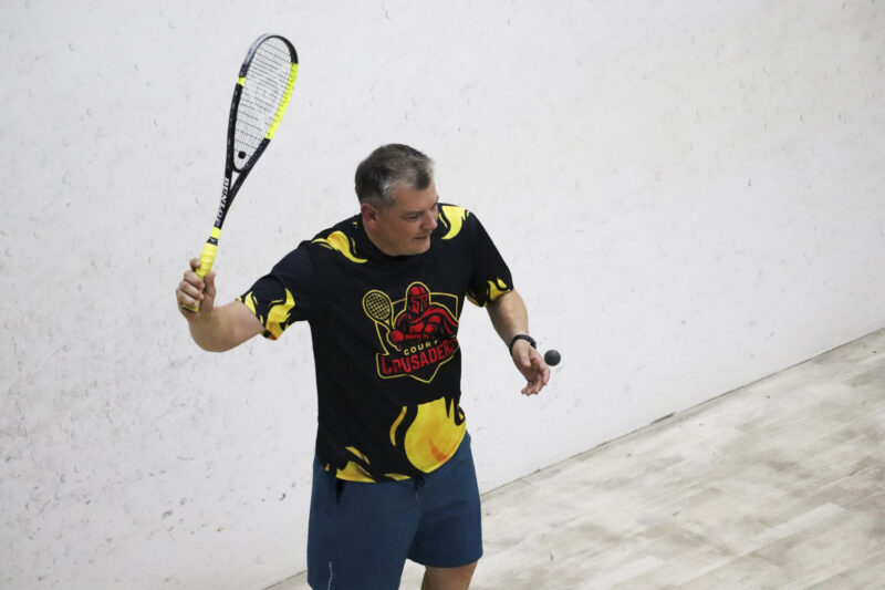 A squash player is captured in action on the squash court.