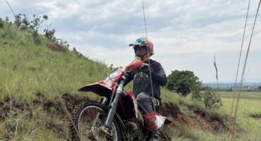 Image of a motorbike rider driving uphill in a field.