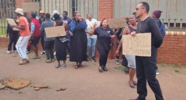 A large group of people gather outside of the Newcastle District Court holding placards opposing bail.