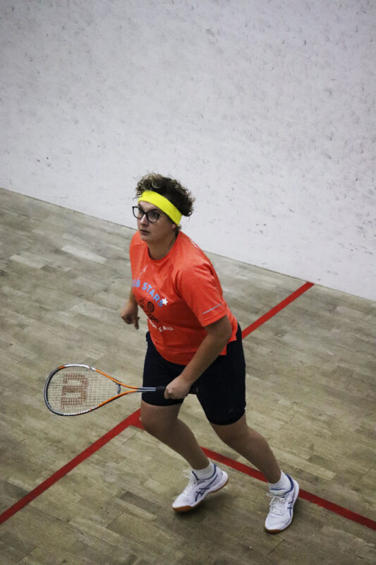 A squash player is captured in action on the squash court.