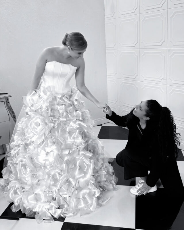 A woman is pictures styling another women's dress. Photo is in black and white.
