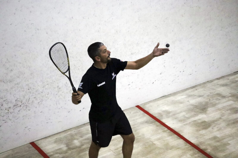 A squash player is captured in action on the squash court.