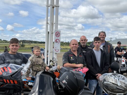 Image of men and young boys standing at their motorcycles, dressed in leather.