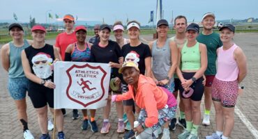 Image of all the runners after an early-morning long run, dressed in running gear and holding the Vryheid Athletic Club banner.