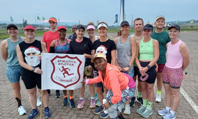 Image of all the runners after an early-morning long run, dressed in running gear and holding the Vryheid Athletic Club banner.