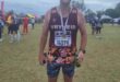 Image of male runner dressed in Vryheid Athletic Club attire with a medal around his neck.
