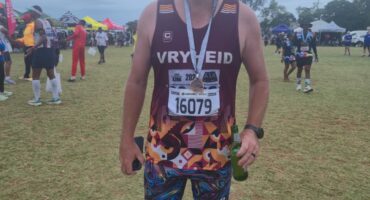Image of male runner dressed in Vryheid Athletic Club attire with a medal around his neck.