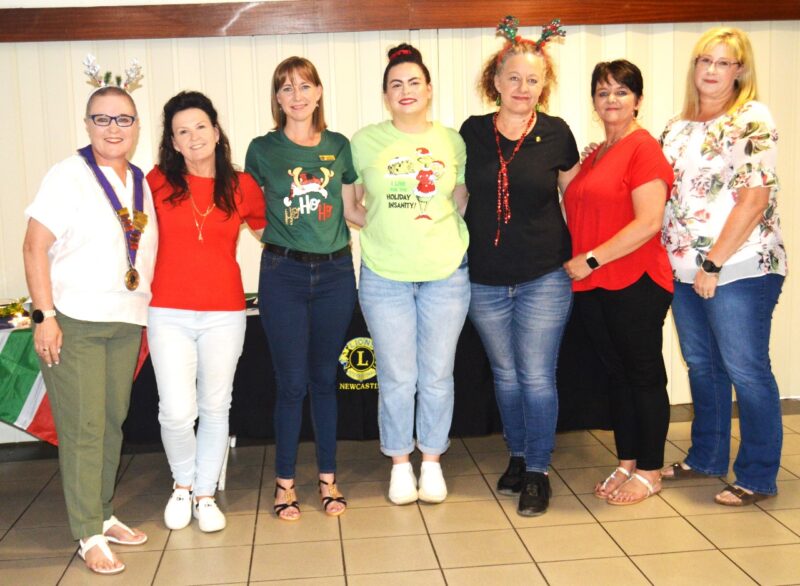 A group of women are photographed in cheerful, Christmas themed attire.