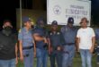 Several police officers stand in front of the Newcastle Police Station in their uniforms at night.