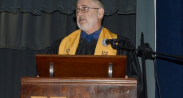 Image of Andries Gregory retiring teacher in academic gown.