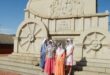 Image of traditionally Boer women in front of the concrete ox wagon at Blood River.