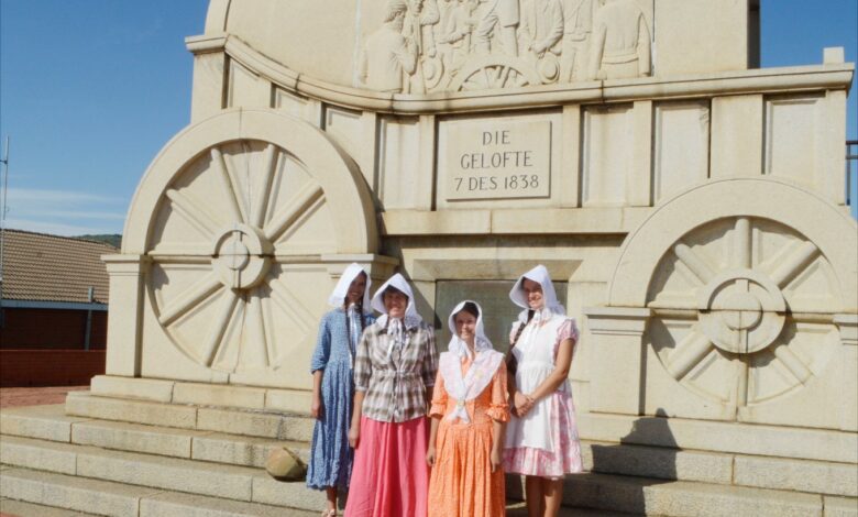 Image of traditionally Boer women in front of the concrete ox wagon at Blood River.