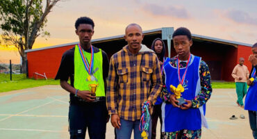 An image of Sifiso Mtshali who hosted a tournament to help a boy child and two boys holding their medals after winning at the soccer tournament.