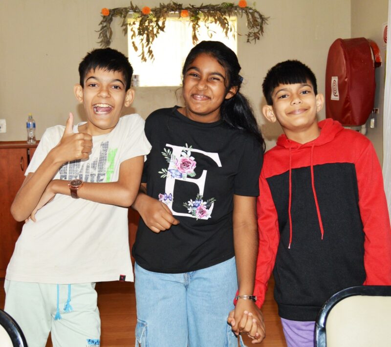 Three children appearing to be very excited pose for a picture during a Christmas Bazaar.