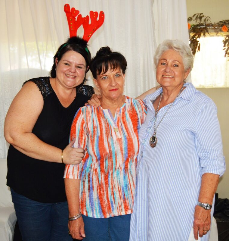 Three people appearing to be very excited pose for a picture during a Christmas Bazaar.