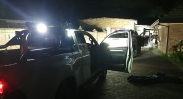 Image of several suspects being arrested outside a house by police.