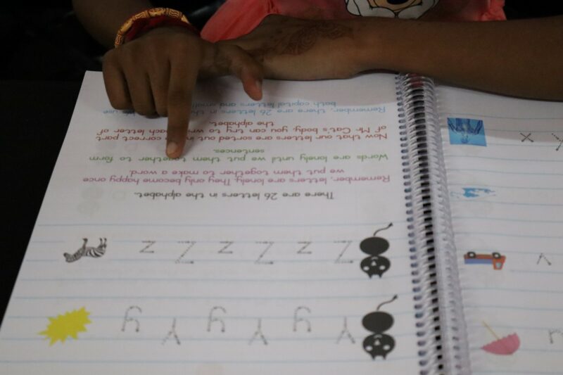 Close-up of child’s hands following letter-writing exercises.