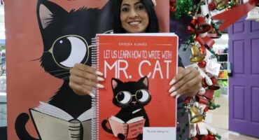 Teacher holds children’s literacy book at launch event.