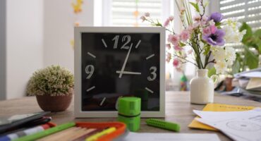 Desk with clock, stationery and flowers preparing for back to school.