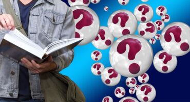 Student reads a book while question marks float nearby.