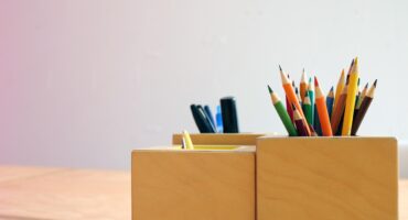 Coloured pencils and pens stored in wooden desk holders
