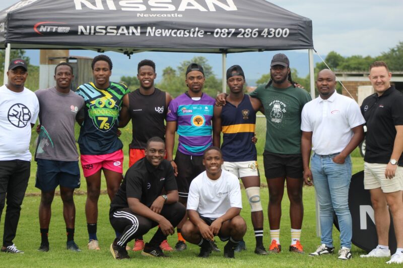 A team photo taken of rugby players posing with their sponsors, NTT Nissan Newcastle.
