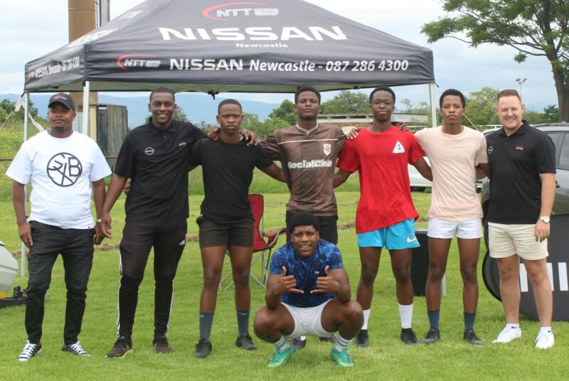 A team photo taken of rugby players posing with their sponsors, NTT Nissan Newcastle.