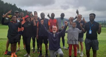 Image of men, women and children with their hands in the air celebrating after their parkrun.