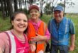Image of two women with a man in their parkrun volunteer shirts in pink, orange and blue.