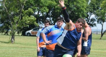 Image of a learner in blue athletic gear in action at shot put.