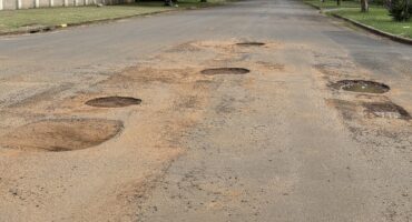 Image of a short piece of a street in the residential area of Vryheid, riddled with potholes.
