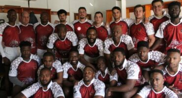 Image of rugby players in a group dressed in maroon and white rugby jerseys.