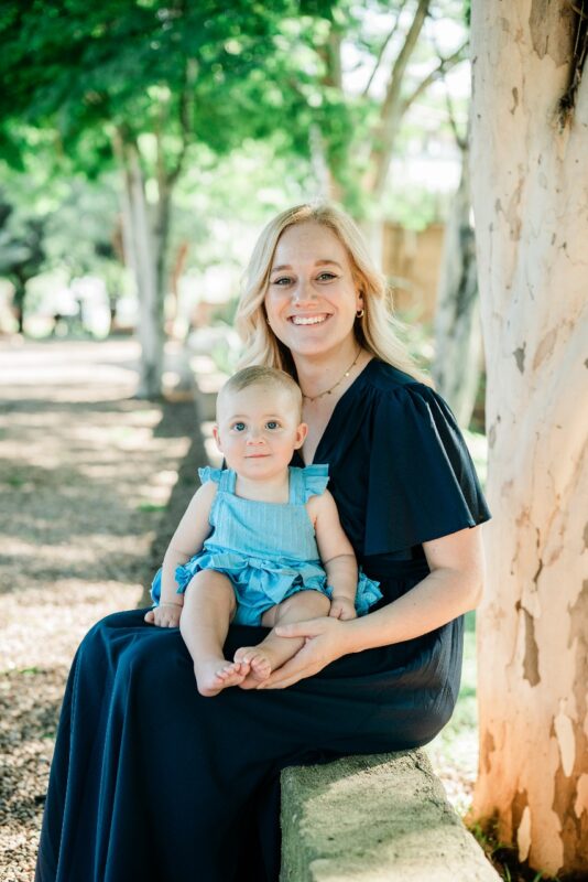 A portrait photo of a woman and a baby taken outside in a garden setting.