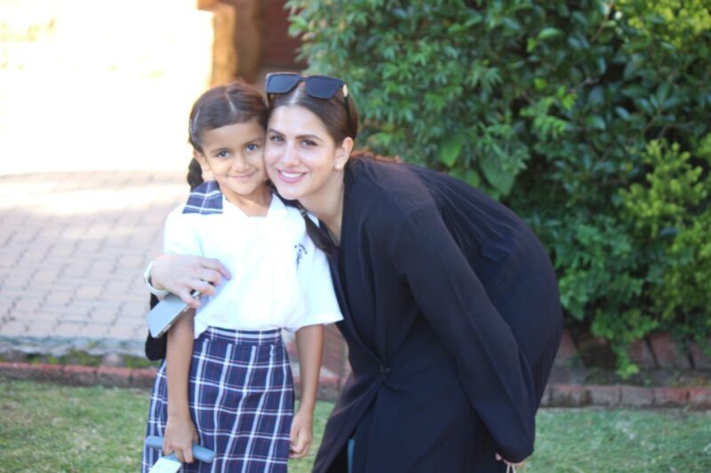 A Grade 1 learner is pictured posing with her mother outside.