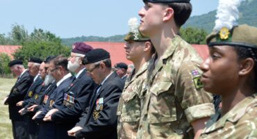 Image of British soldiers and Moth members at attention at a parade at the Rorke's Drift battle site.