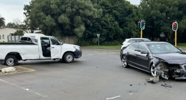 Two vehicles stand damaged after colliding at a traffic light intersection.