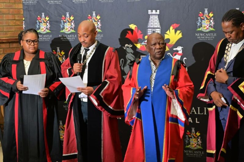 Four municipal officials stand at a special council meeting while a member is being sworn in.