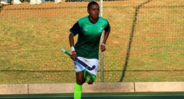 Sphesihle Khaba runs with a hockey stick during a match in his Newcastle High School kit.