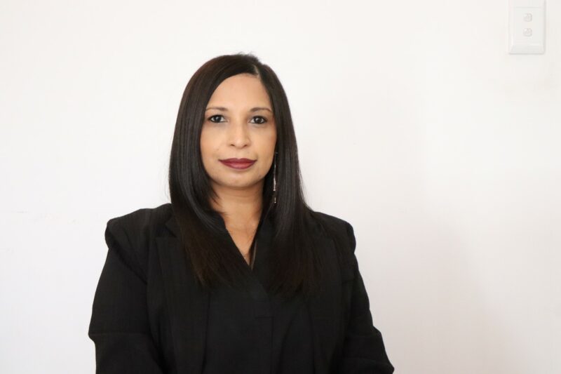 A woman who works at the Newcastle Advertiser dressed in their formal black uniform in front of a white background.