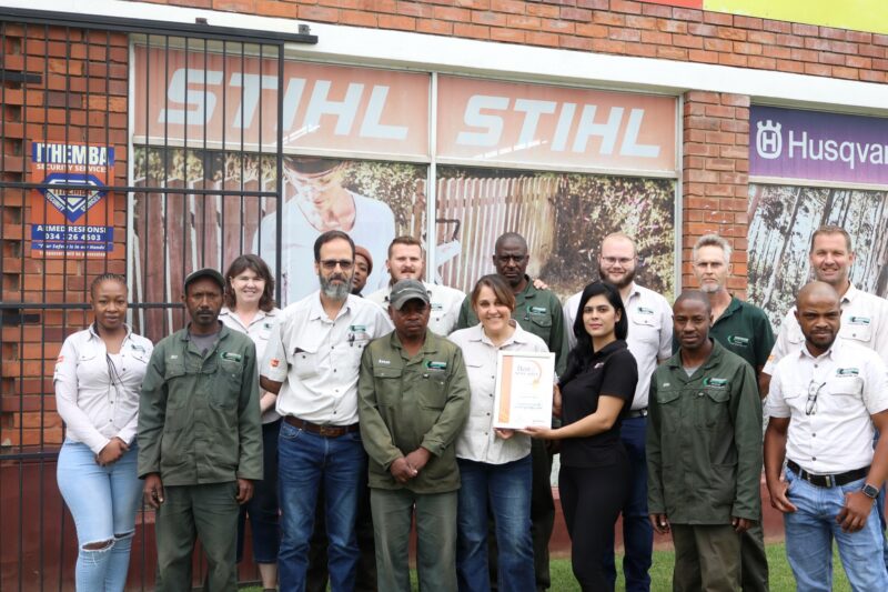 A group of people receiving a certificate from a Caxton Employee.
