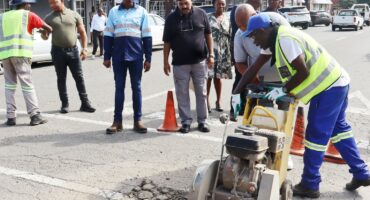 Image of workers completing repairs on roads in Dundee with councillors observing.