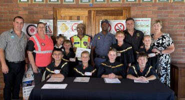 Image of young learners dressed in magistrate' clothes with police and RTI and teachers.