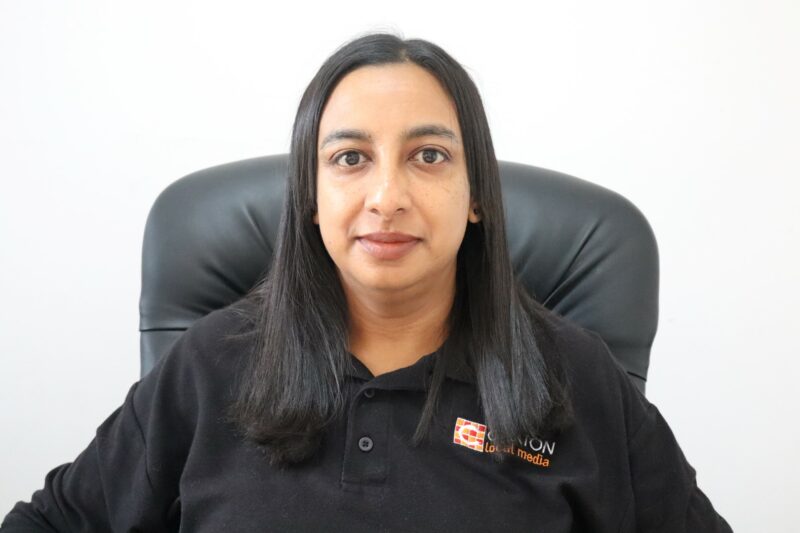 A woman who works at the Newcastle Advertiser dressed in their formal black uniform in front of a white background.