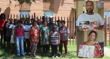 A group of tenants of the Suryaville Municipal Flats pose outside the building under a tree.
