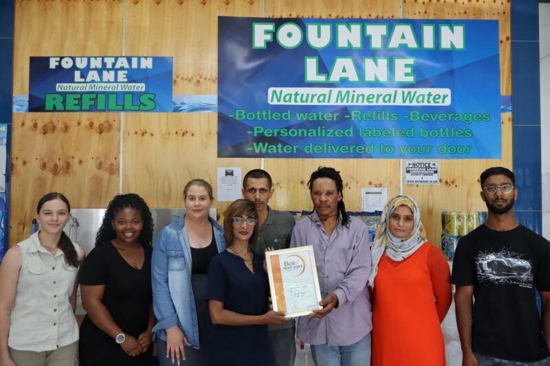 A group of people receiving a certificate from a Caxton Employee.