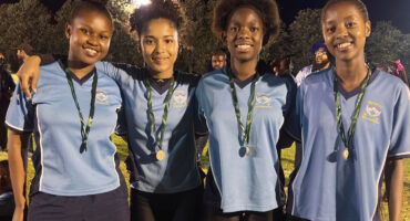 Image of school girls who ran in a relay event wearing medals.
